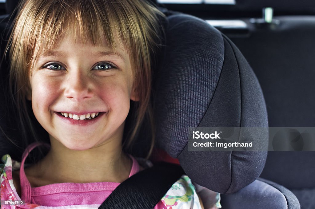 Smiling girl in child car seat Smiling little girl sitting in car child seat. People Stock Photo