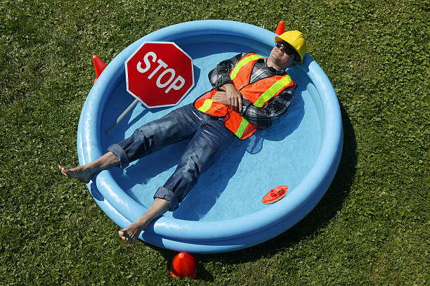 heat wave construction worker in swimming pool construction worker lying down in a swimming pool heat wave photos stock pictures, royalty-free photos & images