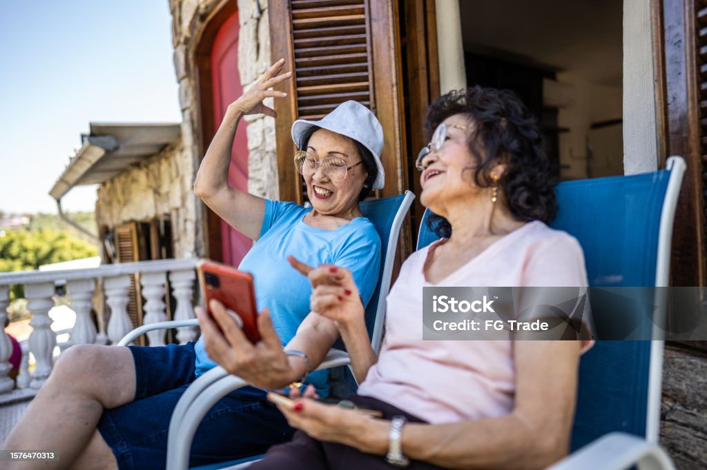 Senior friends using mobile phone on hotel balcony Retirement Stock Photo