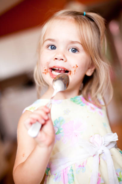Little girl taste eclair pastry like a pro - smell, bite, eat.