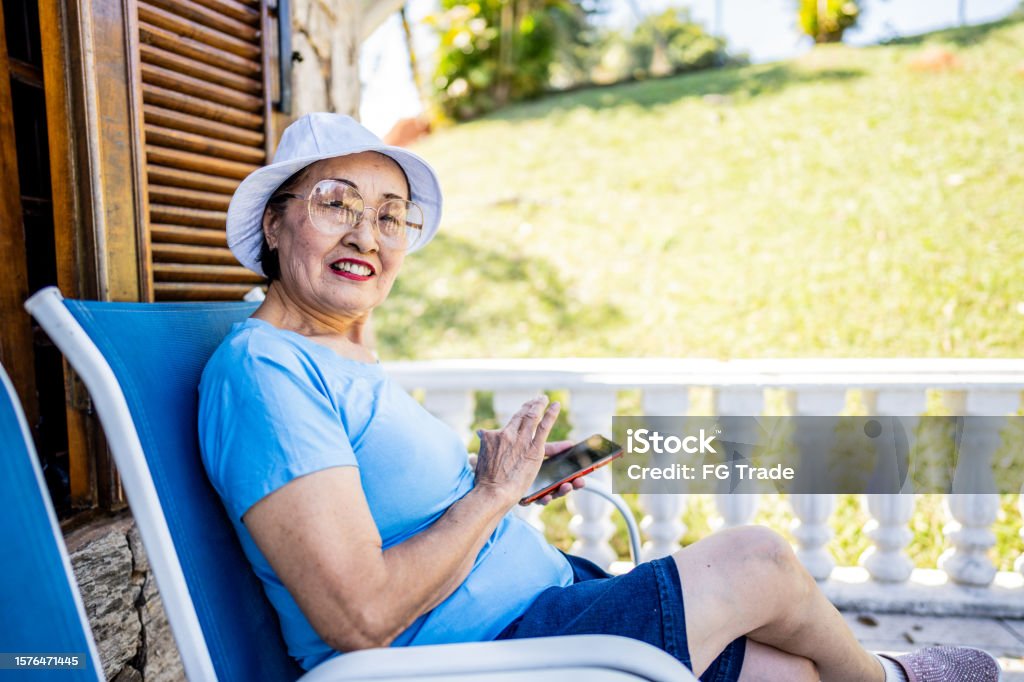 Portrait of a senior woman using mobile phone in a balcony Japanese Ethnicity Stock Photo
