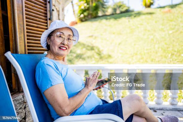Portrait Of A Senior Woman Using Mobile Phone In A Balcony Stock Photo - Download Image Now