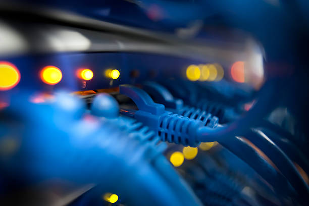 Closeup Of A Server Network Panel with Lights and Cables Selective focus closeup view of cables plugged into a server network panel with lights indicating activity. Photographed inside an equipment room.  Canon 5D MarkII. The file has been meticulously retouched in Photoshop eliminating dust and unwanted flaws. I have over 22 years experience as a photo retoucher. computer cable stock pictures, royalty-free photos & images