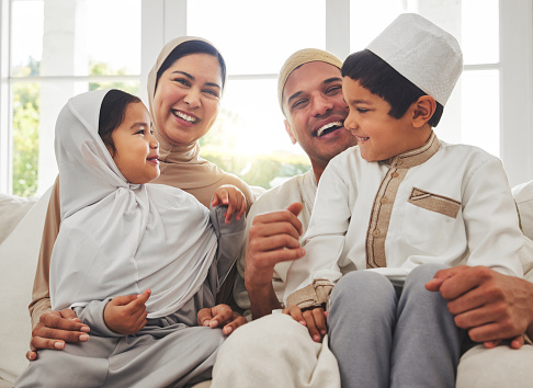 Happy family, Islam and laughing on couch for Eid with mom, dad and kids with home culture in Indonesia. Muslim man, woman in hijab and children smile, funny bonding on sofa together in living room.