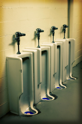 Urinal at an old army base - there are four in a line, side by side in a utilitarian center block wall and a gray coated floor. The selective focus makes the farthest one out of focus, the guard at the bottom is blue with a pink urinal cake. This photo has been stylized and digitally enhanced through some manipulation of the file, giving the edges an aged darker border look, and the edgy action of a zoom motion blur effect. And the colors are slightly cross processed, giving it a very contemporary and edgy feel.