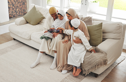 Family house, children or Muslim parents with tablet for elearning, Islamic info or studying in Allah or God. Child development, dad or Arab mom with young kids reading online ebook on social media
