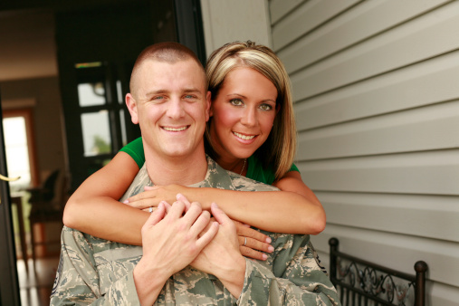 Woman hugging a soldier in military camouflage uniform while he leaving for army