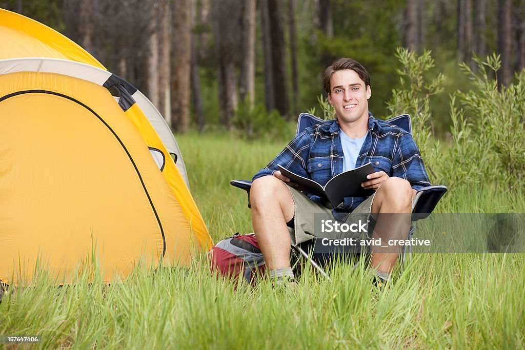 キャンプ：若い男性リーティングのテント - 1人のロイヤリティフリーストックフォト