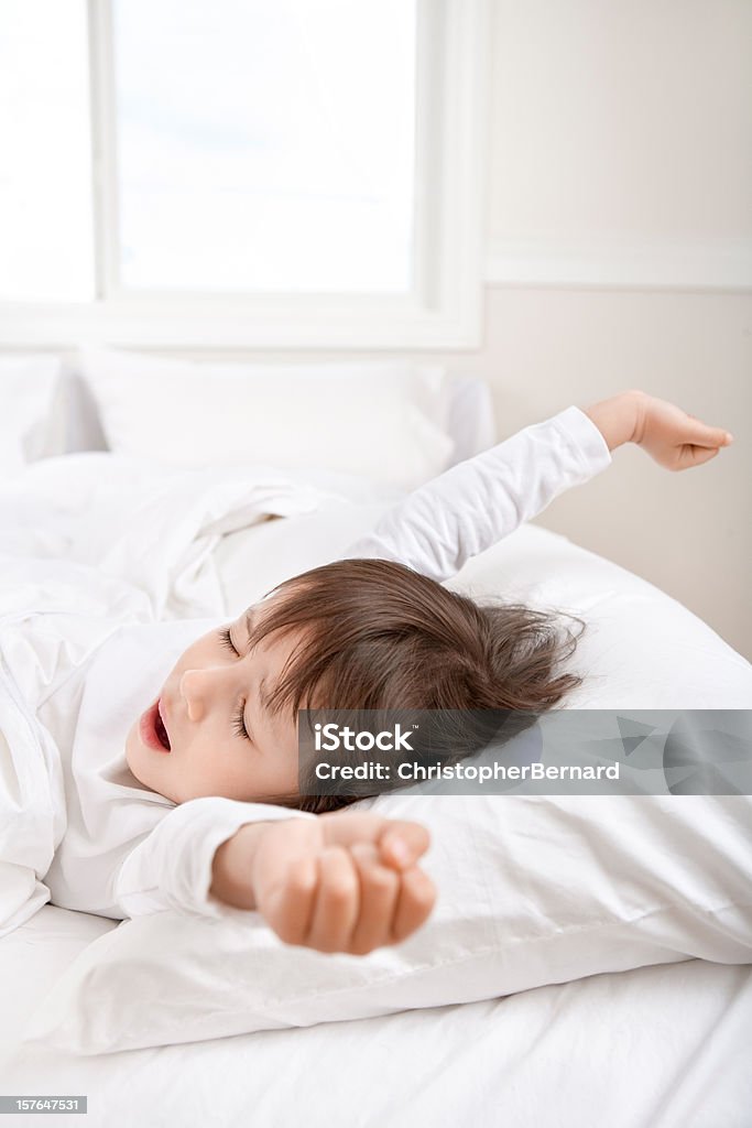 Menina estendendo-se na cama - Foto de stock de Colchão royalty-free