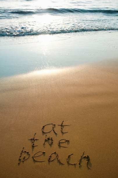istock At the beach written on sand during sunset, ocean surf 157647687