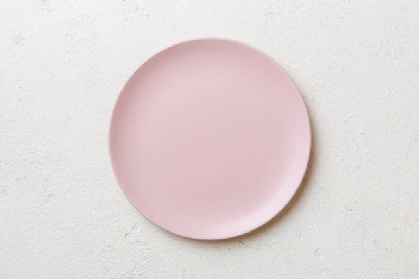 istock Top view of empty pink plate on cement background. Empty space for your design 1576478910