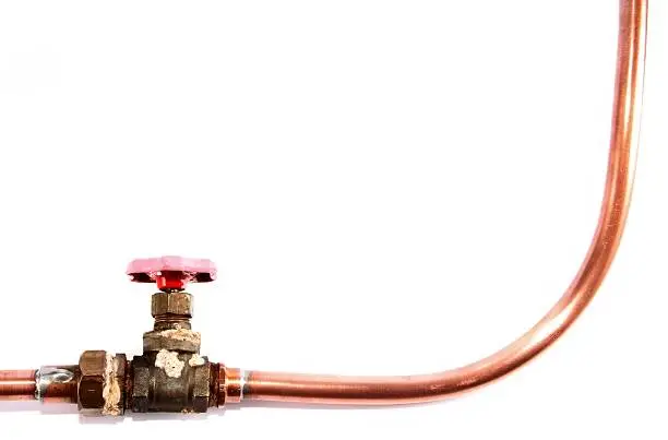 old industrial copper pipeline with red valve isolated