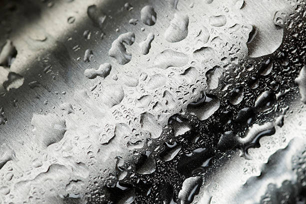 Water droplets collecting on waved metal stock photo