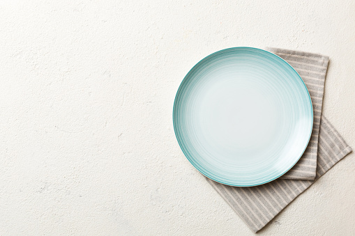 Top view on colored background empty round Blue plate on tablecloth for food. Empty dish on napkin with space for your design.
