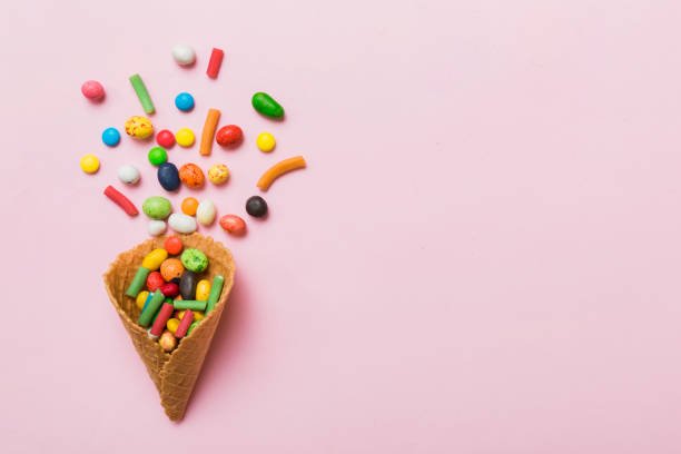 istock waffle cone full of assorted traditional candies falling out on colored background with copy space. Happy Holidays sale concept 1576480085