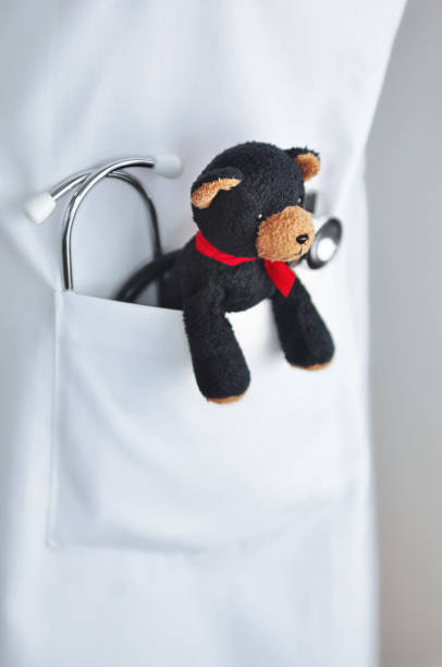 Stethoscope and child's teddy bear in doctor's lab coat pocket stock photo