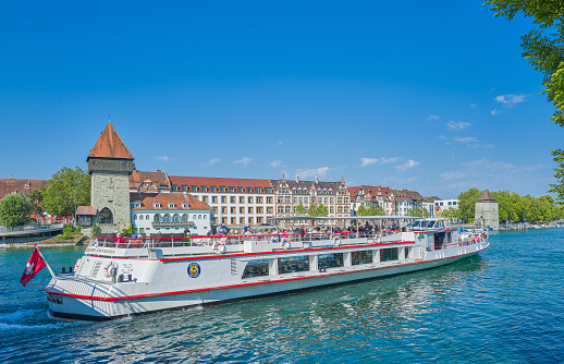 Constance, Germany - June 15,2023: A classic boat for tourists along the Rhine River with the Rhine Gate Tower and the Powder Tower  in the background