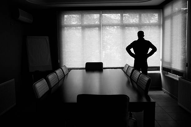 silhouette der einsame geschäftsmann, stehend im büro mit konferenztisch - bankrott stock-fotos und bilder