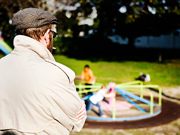 Possible pedophile watches kids play in park stock photo