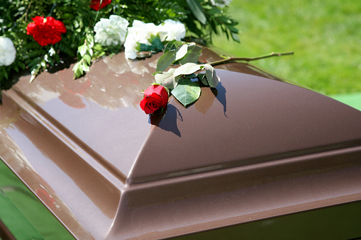A single brown casket with a spray of flowers.