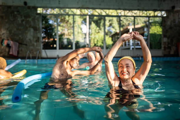 istock Senior friends doing stretching exercises on a pool at a resort 1576485632