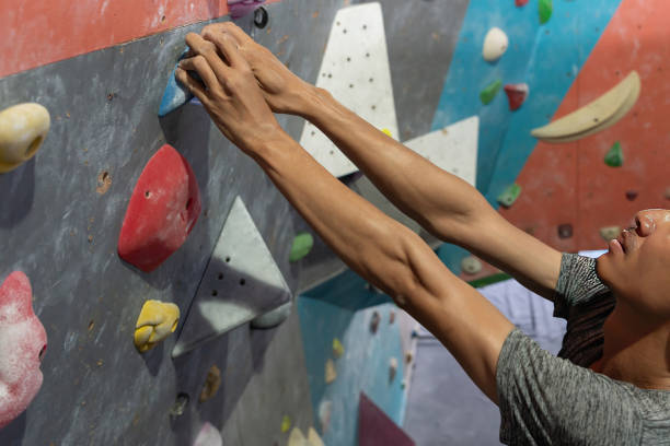 Man climbing on wall training in gym, active sporty male practicing rock climbing on artificial rock in extreme sport, bouldering, climbing wall, climber is training, rock climbing in the city, strong