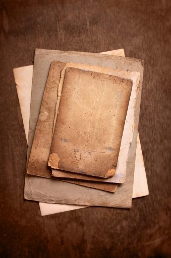 Very old and torn antique book with no cover on grunge wooden background