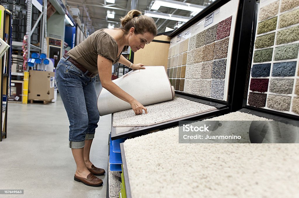 Una mujer joven seleccionando una alfombra de muestras - Foto de stock de Moqueta libre de derechos