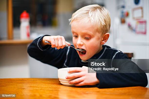 7 Anos De Idade Menino Loiro Aspecto Em Tigela De Cereais Ansiosamente - Fotografias de stock e mais imagens de 6-7 Anos