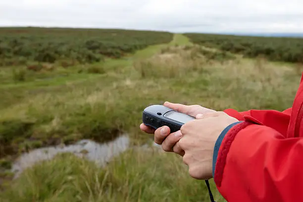 Definitive image for geocaching - man holding GPS device in wild countryside