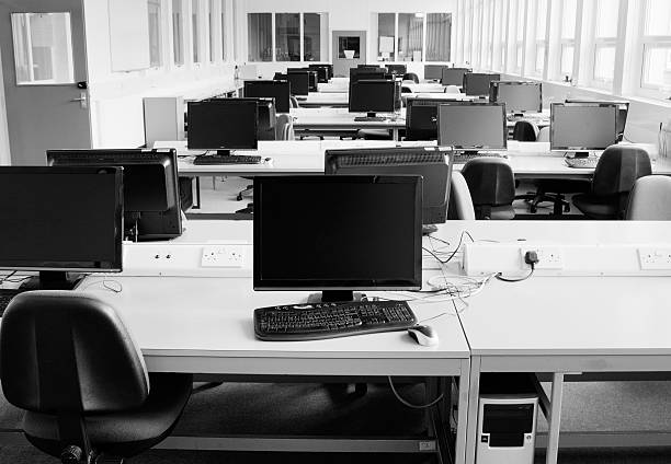 Computer room: PCs arranged on several desks Large depth of focus. Computer room in a University, brightly lit, with nobody in it. A workstation is visible in the foreground computer store stock pictures, royalty-free photos & images