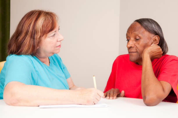 assistente sociale di prendere appunti con una donna anziana - mental health professional senior adult social services mental health foto e immagini stock