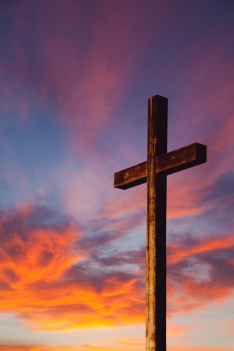 Resistente cruz de madera contra el cielo al atardecer photo