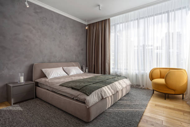 istock Light modern bedroom with comfortable furniture against big window 1576504818