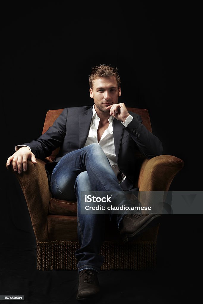 Bellezza di maschio seduto su una poltrona. Immagine a colori - Foto stock royalty-free di Uomini