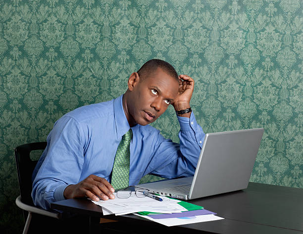 Worried business man with laptop and documents at work Portrait of a worried business man with laptop and documents at work rolling eyes stock pictures, royalty-free photos & images