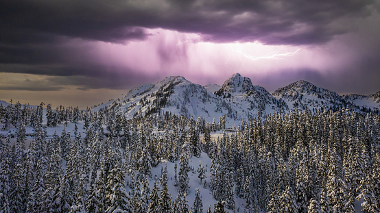 An image of Mt Baker in the North Cascade Mountains covered in snow with lightning bolts in the sky.