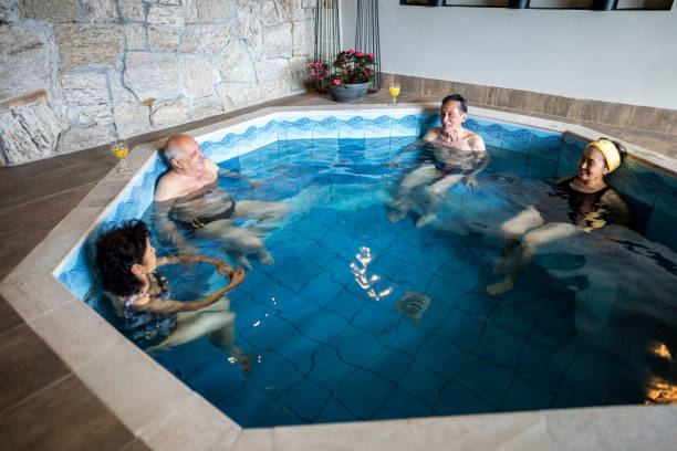 istock Senior friends talking at an indoors resort spa pool 1576507520