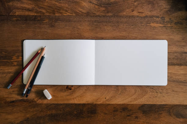 istock Horizontal style blank sketchbook on wooden table with crayons 1576544180