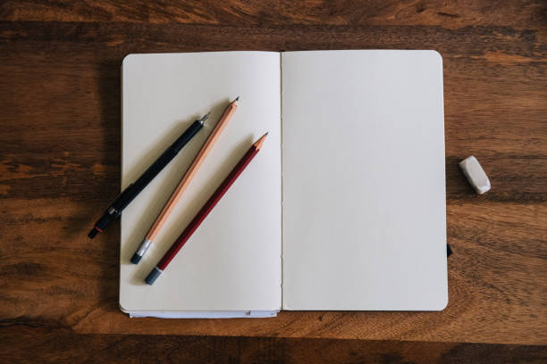 Vertical style blank sketchbook on wooden table with crayons