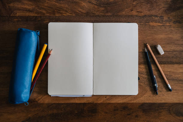 istock Vertical style blank sketchbook on wooden table with crayons 1576544288