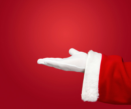 Santa Claus hand presenting your text or product over red background with copy space