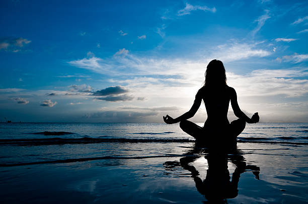 Meditation Silhouette of woman in lotus position sitting in sea and medditating mantra stock pictures, royalty-free photos & images