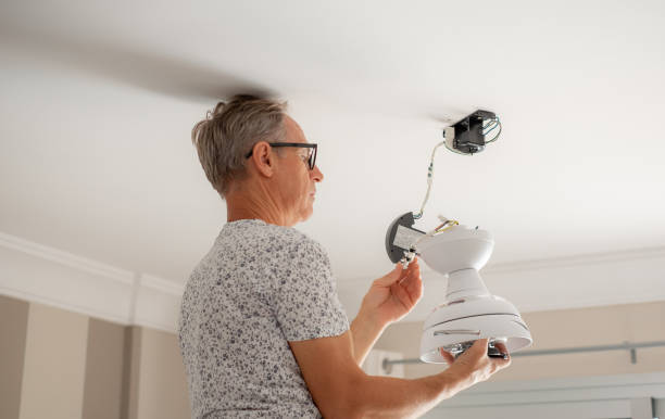 istock Mature experienced electrician man on a stair installing a paddle fan on the ceiling at home 1576573892