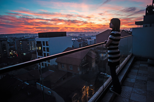 Woman in sunset. Lifestyle concept. Hipster woman on balcony in sunset in city. Leisure lifestyle.