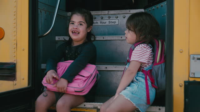 Little girls sitting on school bus talking
