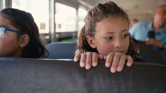 Elementary age kids riding on school bus with teachers and parents