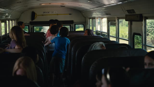 Elementary age kids riding on school bus with teachers and parents