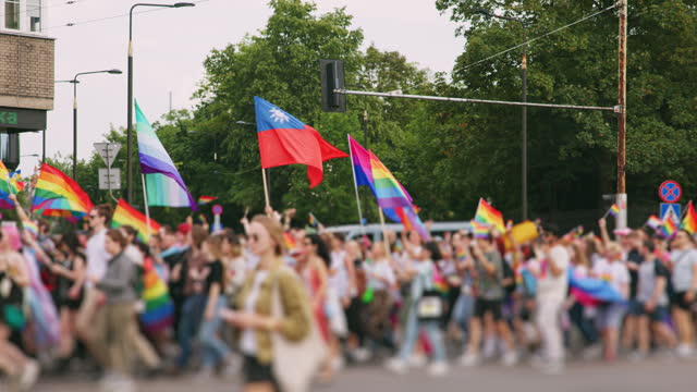 LGBTQIA+ pride parade march. Protestors marching together with rainbow flags and celebrating their identity