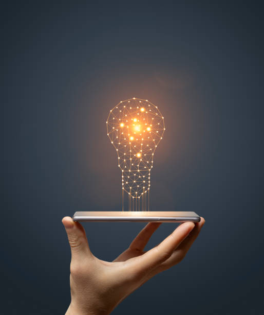 istock Idea concept with hand holding smartphone with glowing light bulb 1576609691